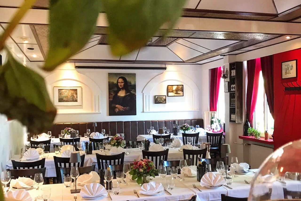 Gastraum mit weißen Tischdecken, Mona-Lisa-Bild und roten Vorhängen